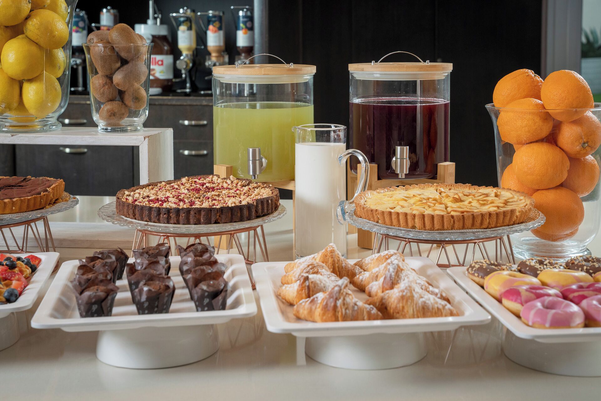 A buffet table with various desserts, including cakes, pastries, and fruit.