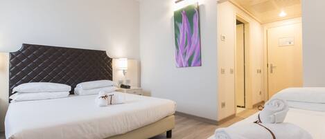 A hotel room with a large bed, bedside tables, a headboard, a painting, and a bathroom door.