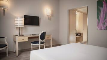 Ein Hotelzimmer mit Bett, Schreibtisch, Stuhl, Fernseher und Kleiderschrank.