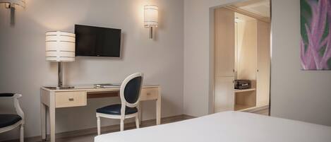 A hotel room with a bed, a desk with a chair, a television, and a wardrobe.