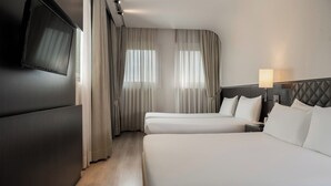 Een hotelkamer met twee bedden, een aan de muur bevestigde televisie en een bedlampje.
