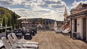 A rooftop terrace with lounge chairs and a view of the surrounding landscape.