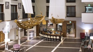 A lobby with a bar area, seating, and a large decorative sailboat.