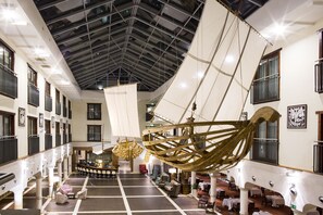 A spacious hotel lobby with a high ceiling, large windows, and a central seating area. - Hotel Król Kazimierz (Kazimierz Dolny)