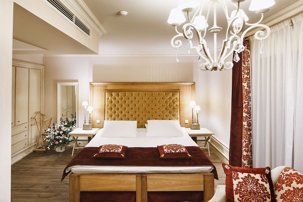 Ein geräumiges Schlafzimmer mit einem großen Bett, einer Kandelaberleuchte und einem hölzernen Kopfteil.