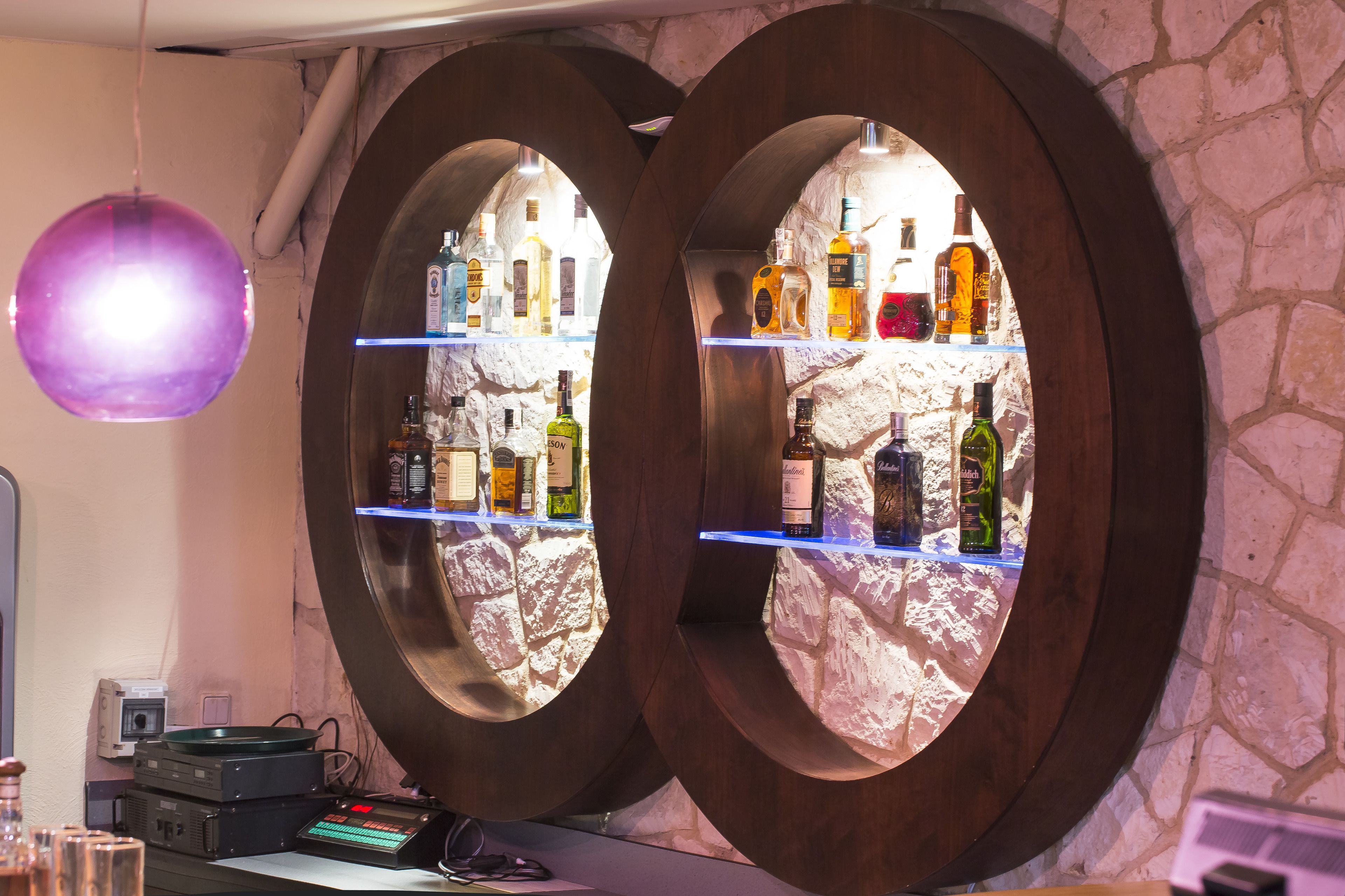 Uma área de bar com duas prateleiras espelhadas exibindo diversas garrafas de bebidas.