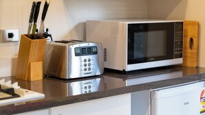 A kitchen with a toaster, a microwave, and a wooden knife block. - Wanaka Springs Lodge (Wanaka)