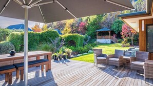 A wooden deck with outdoor furniture, a pergola, and a garden with various plants and a gazebo. - Wanaka Springs Lodge (Wanaka)