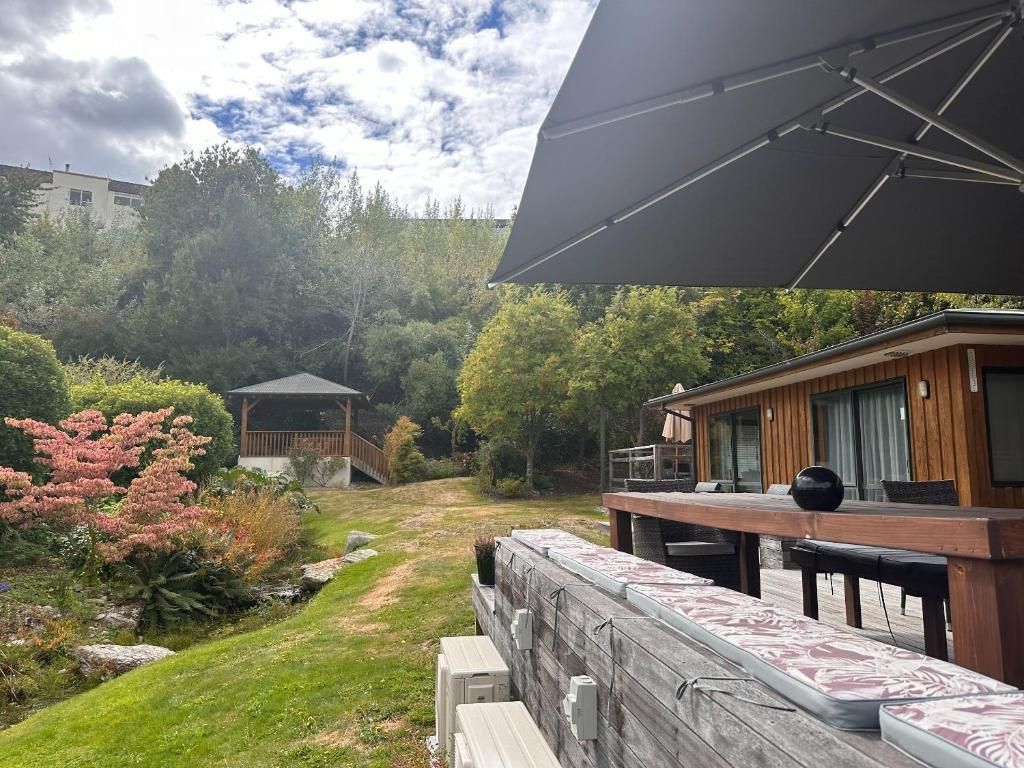 A patio area with a wooden deck, outdoor seating, and a gazebo in a landscaped garden.