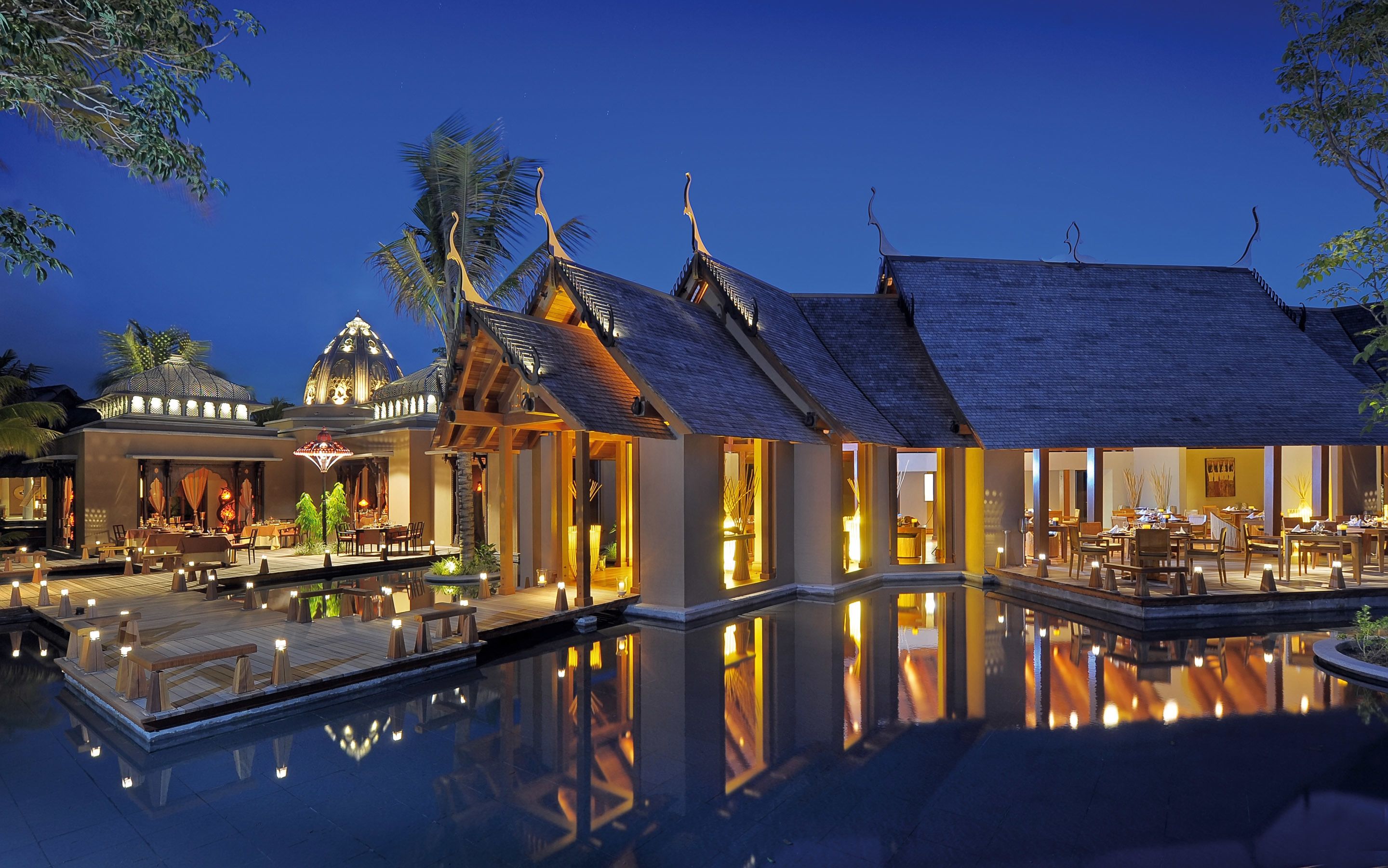 Un resort lujoso con piscina, zona de comedor al aire libre y arquitectura tradicional.