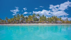 A beach resort with palm trees, beach umbrellas, and a clear blue sky. - Trou aux Biches Beachcomber Golf Resort & Spa (Trou aux Biches)