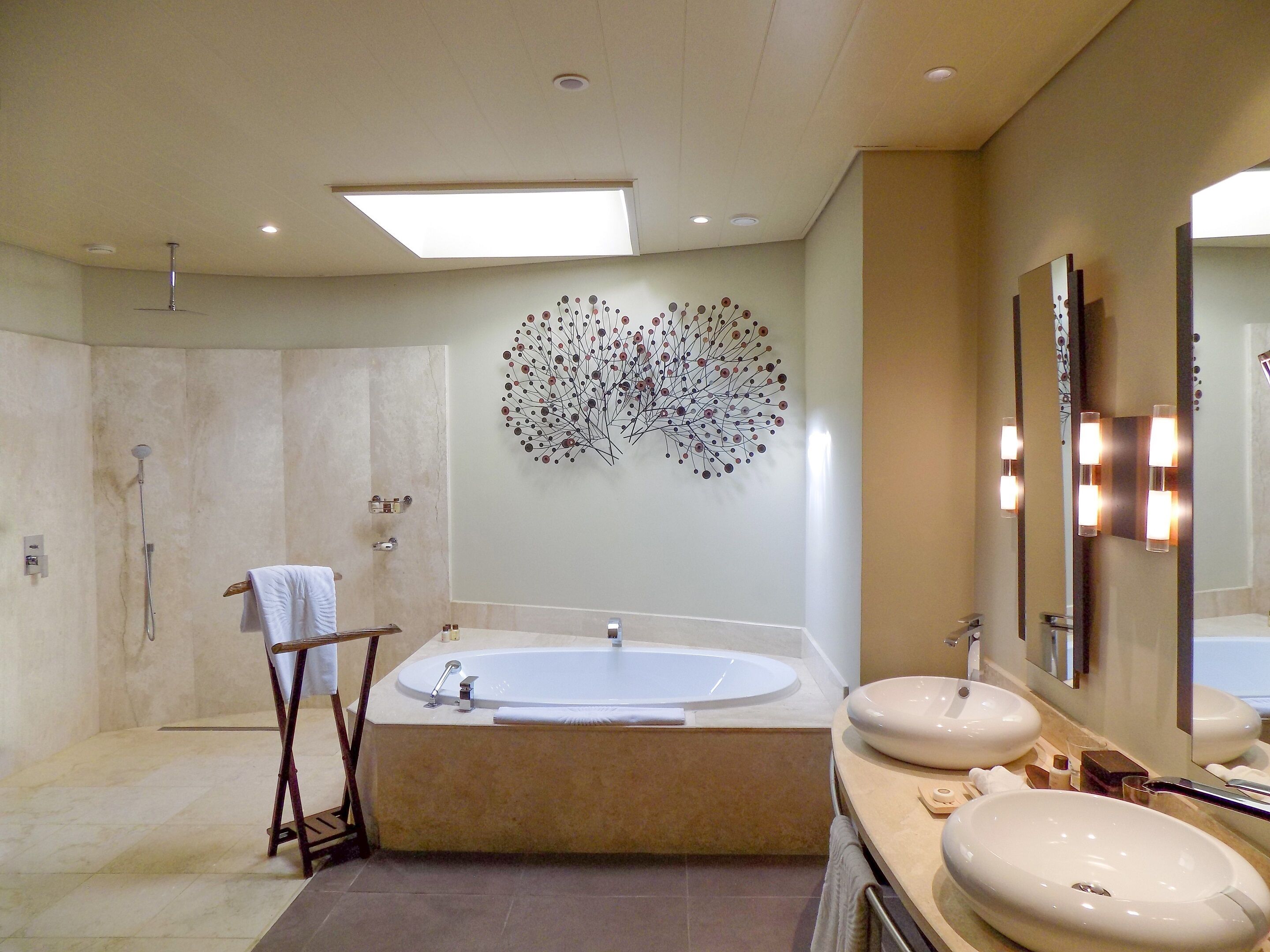 Une salle de bain moderne avec une baignoire sur pieds, deux vasques et un grand miroir fixé au mur.