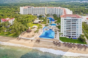 Un complejo turístico con varias edificaciones, una piscina grande y una zona de playa.