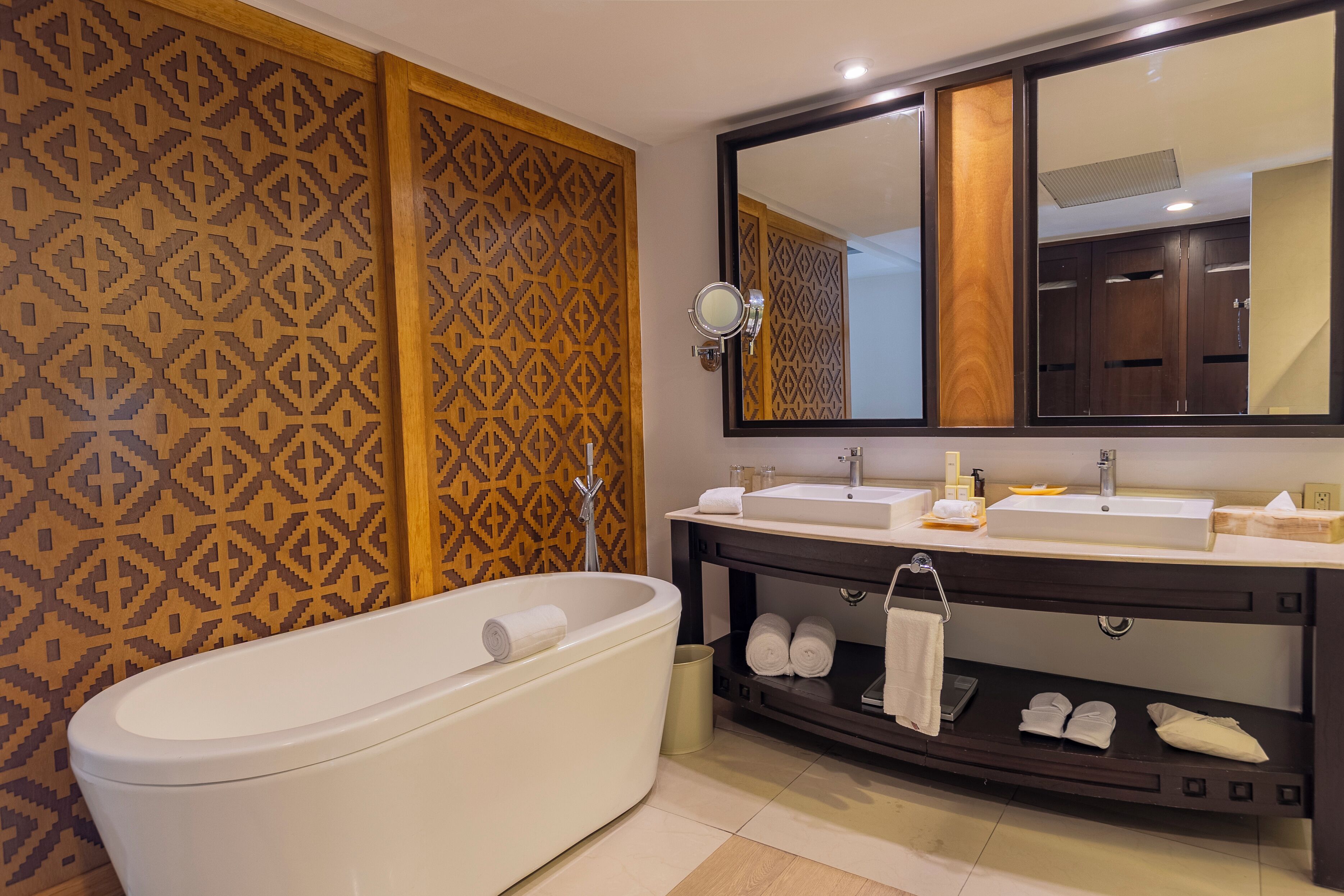 A modern bathroom with a freestanding bathtub, a large mirror, and a vanity with a sink and towel rack.