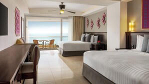 Ein Hotelzimmer mit einem großen Bett, einem Schreibtisch und einem Sessel. Es gibt einen Balkon mit Meerblick.
