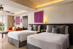 Habitación de hotel con dos camas, un sofá, un escritorio y un ventanal grande.