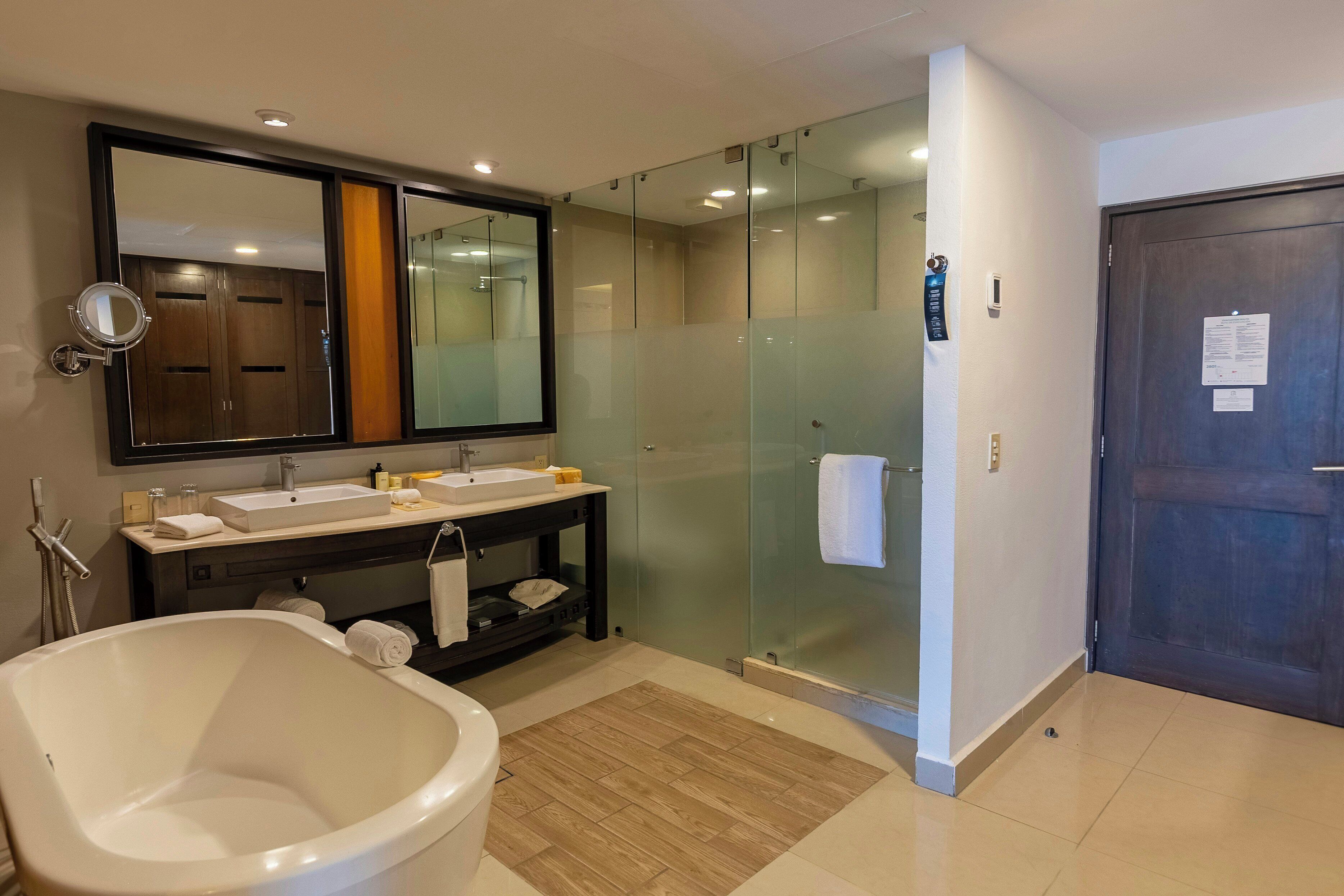 Une salle de bain moderne avec une baignoire, une douche à parois de verre et un meuble-lavabo avec un miroir.