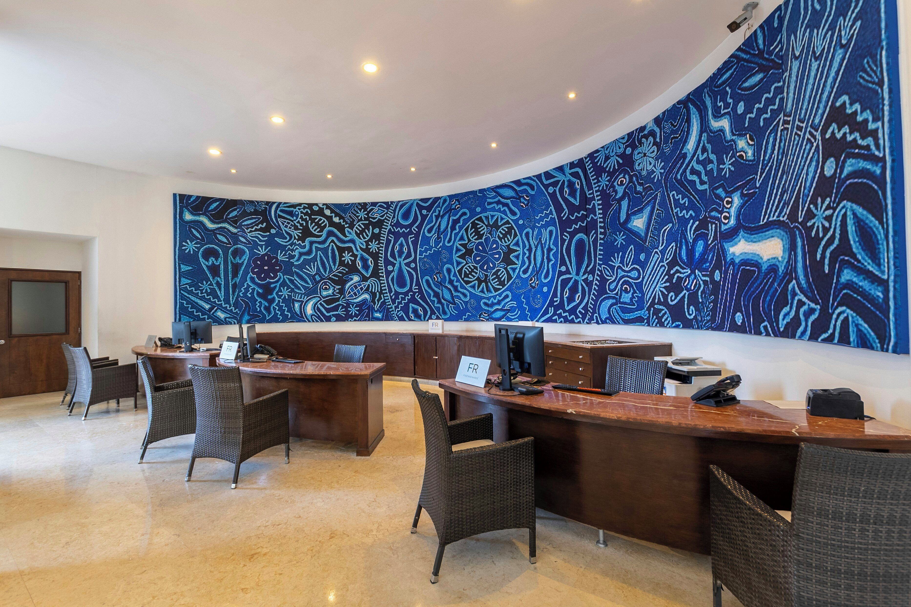 A modern reception area with a large abstract mural, multiple workstations, and comfortable seating.