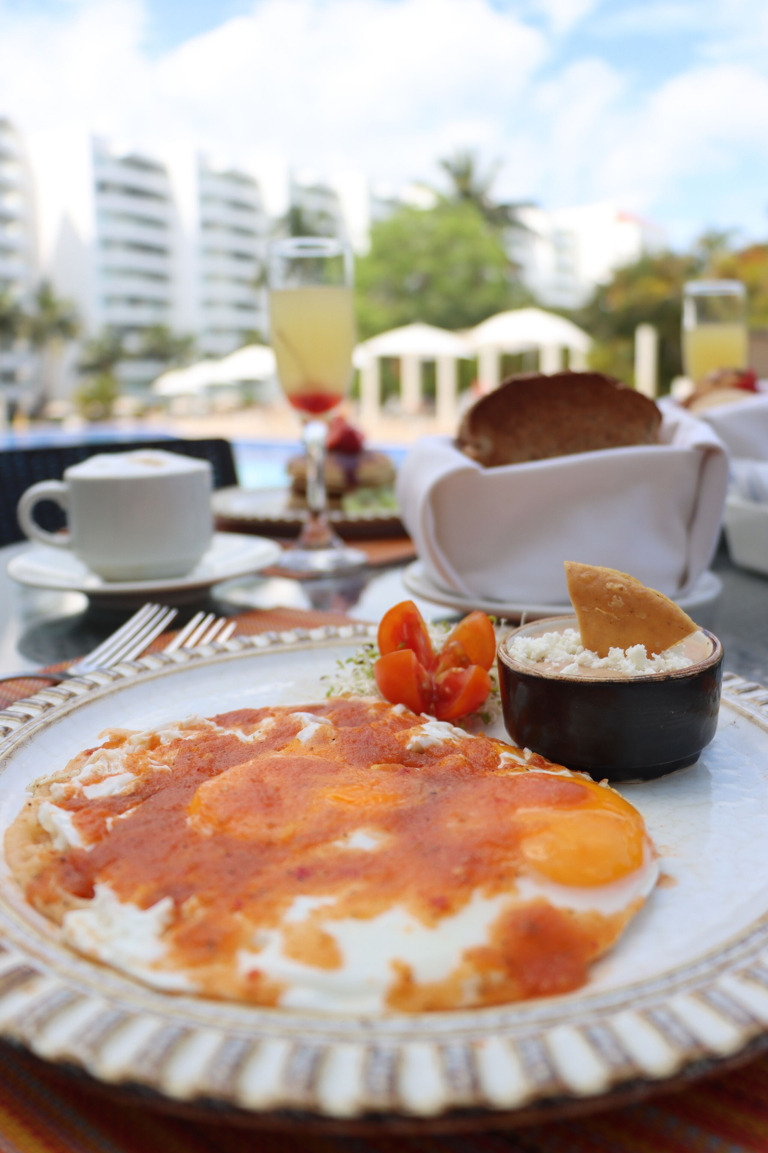 A breakfast setting with a plate of food, a cup, and a glass of drink on a table.