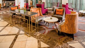 A spacious lobby with a marble floor, comfortable seating, and large windows with curtains. - Southern Sun Sandton (Sandton)