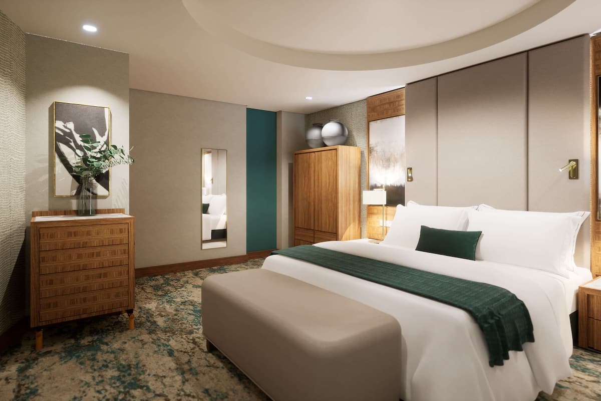 A hotel room with a large bed, a wooden dresser, a mirror, and a wall-mounted TV.