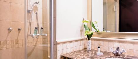 Une salle de bain avec une douche à parois de verre, un lavabo en marbre et un miroir au-dessus du lavabo.