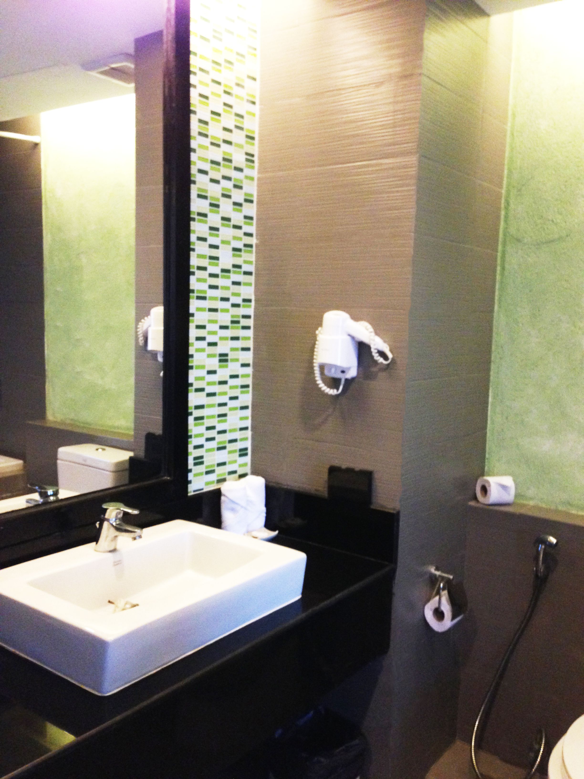 Une salle de bain avec un lavabo blanc, un porte-serviettes, un miroir et des toilettes.