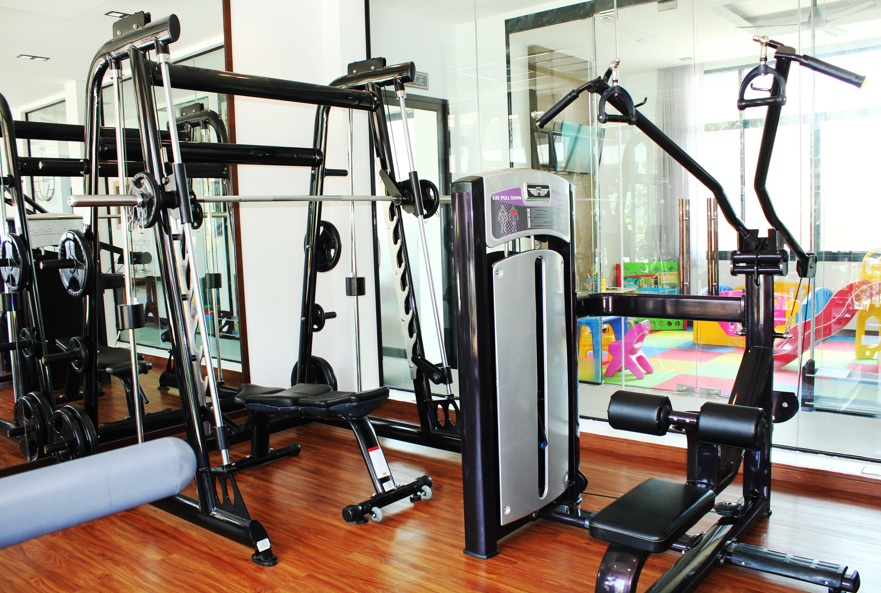 A gym with various exercise equipment, including a bench press, leg press, and cable machine.