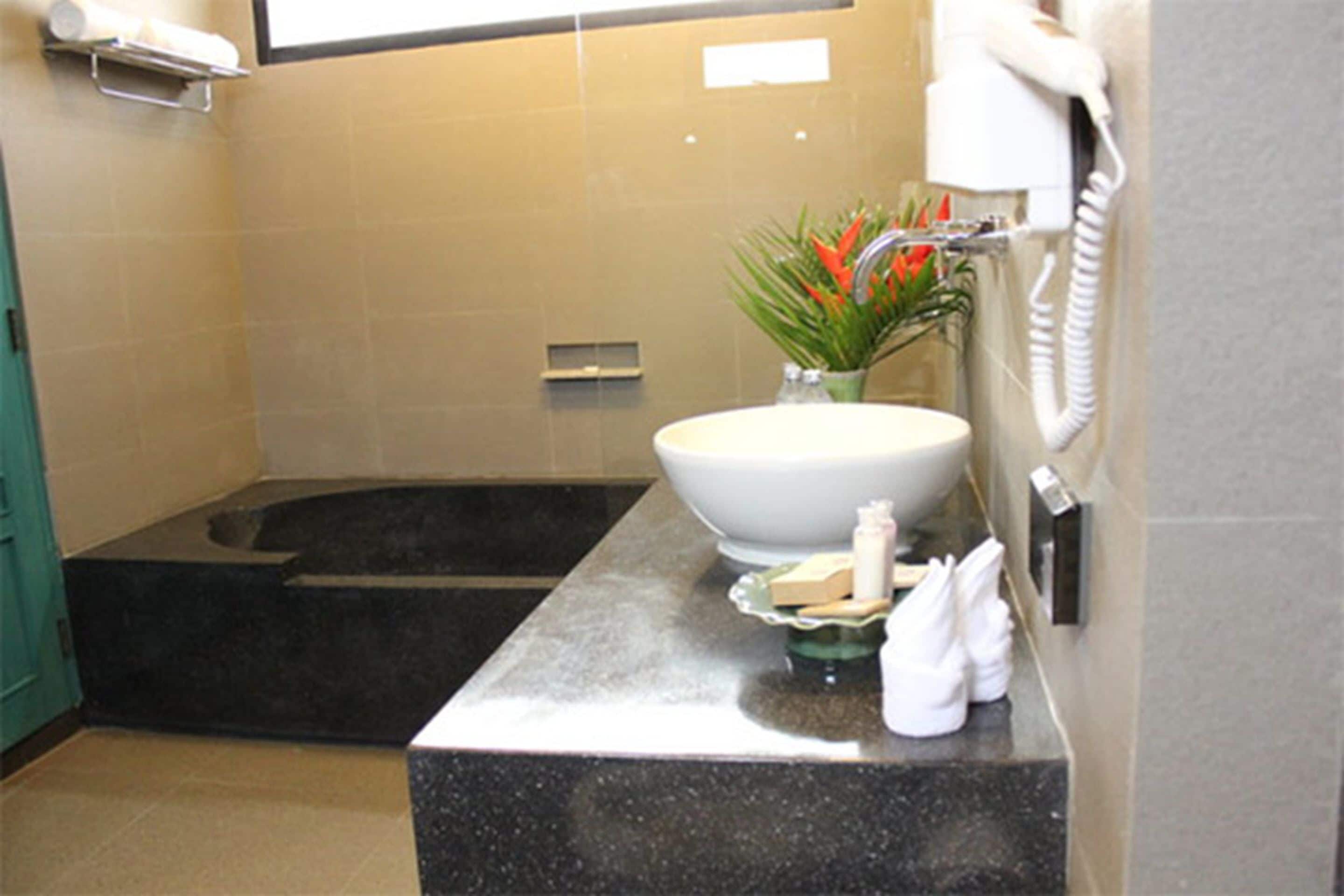 Une salle de bain équipée d’une baignoire, d’un lavabo, d’un sèche-cheveux et d’articles de toilette.
