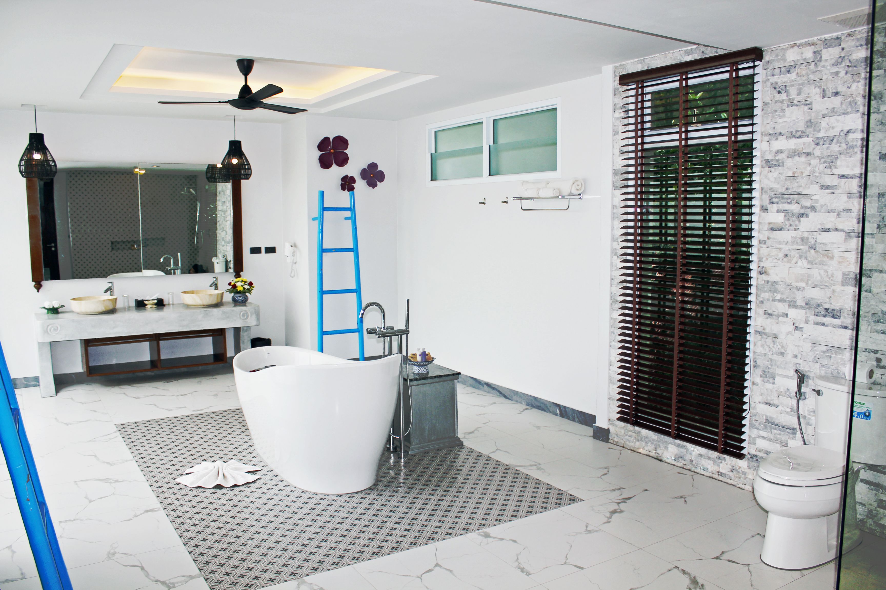 A modern bathroom with a freestanding bathtub, a vanity with a mirror, and a toilet.