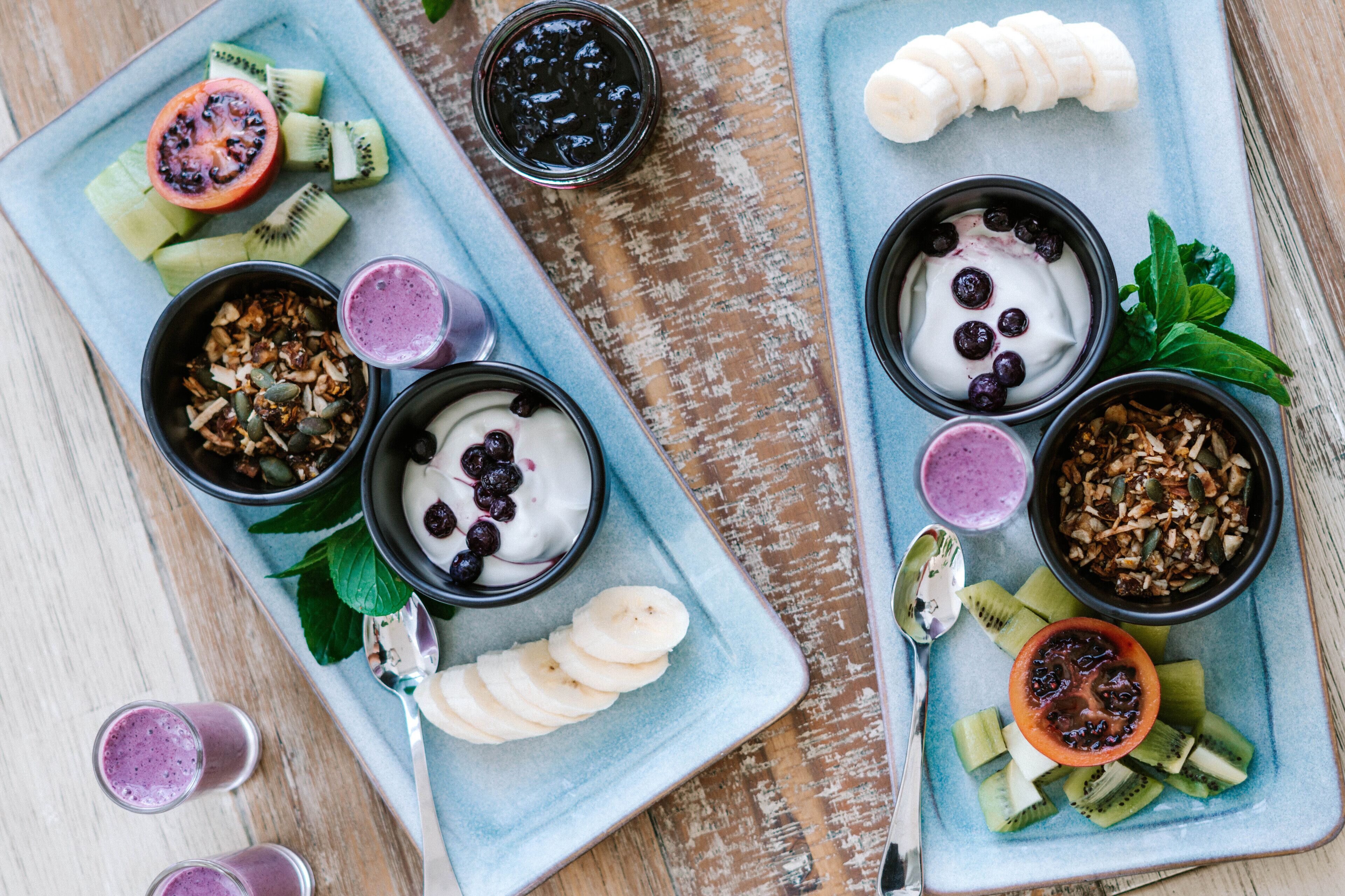A breakfast spread with yogurt, granola, and fresh fruits on a blue plate.