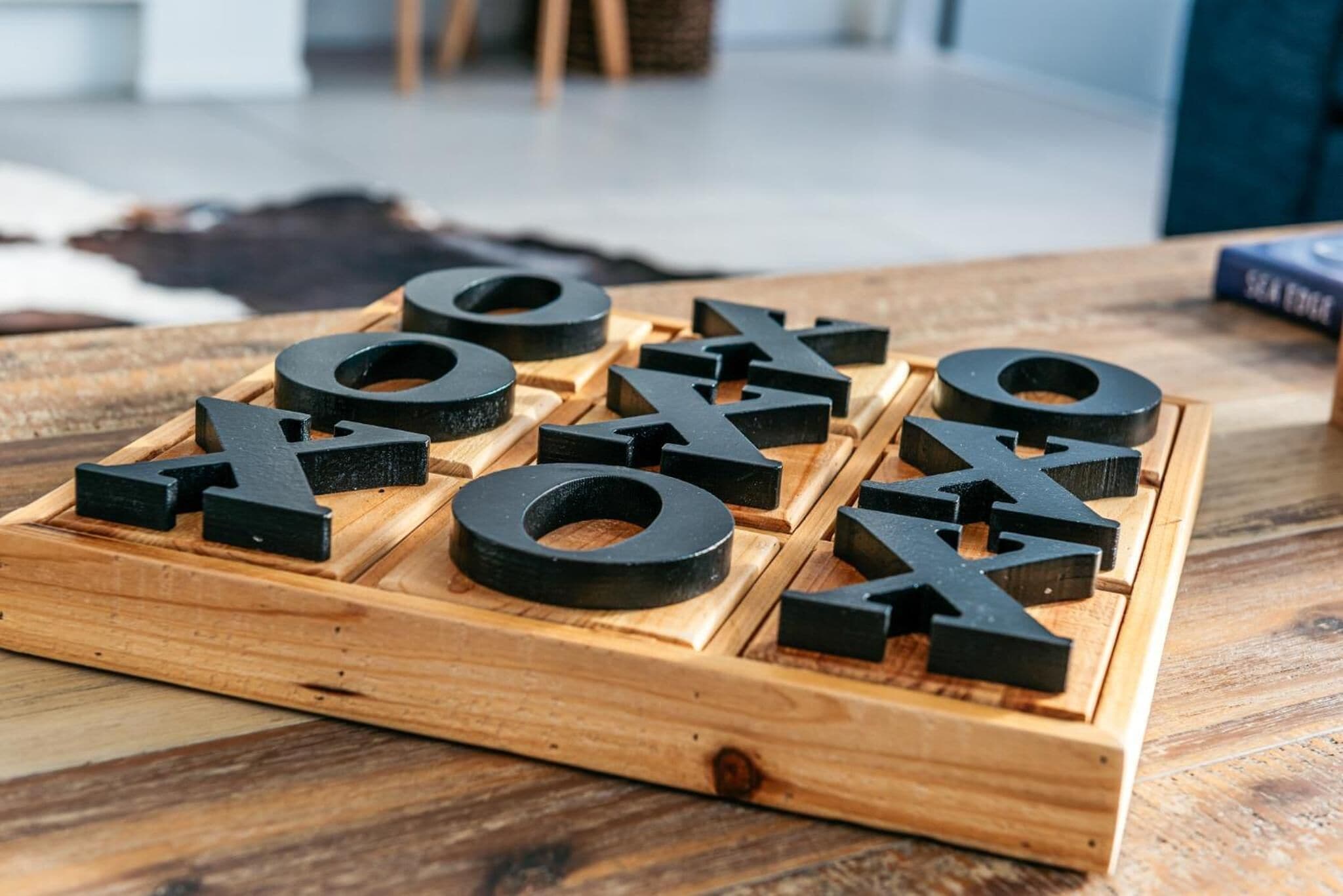 Una tabla de madera con piezas en forma de letras negras dispuestas para deletrear 'HOME'.