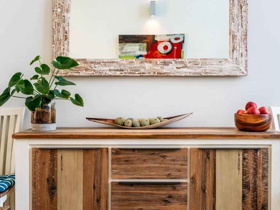 Um console de madeira com uma tigela de objetos redondos e uma planta em vaso.