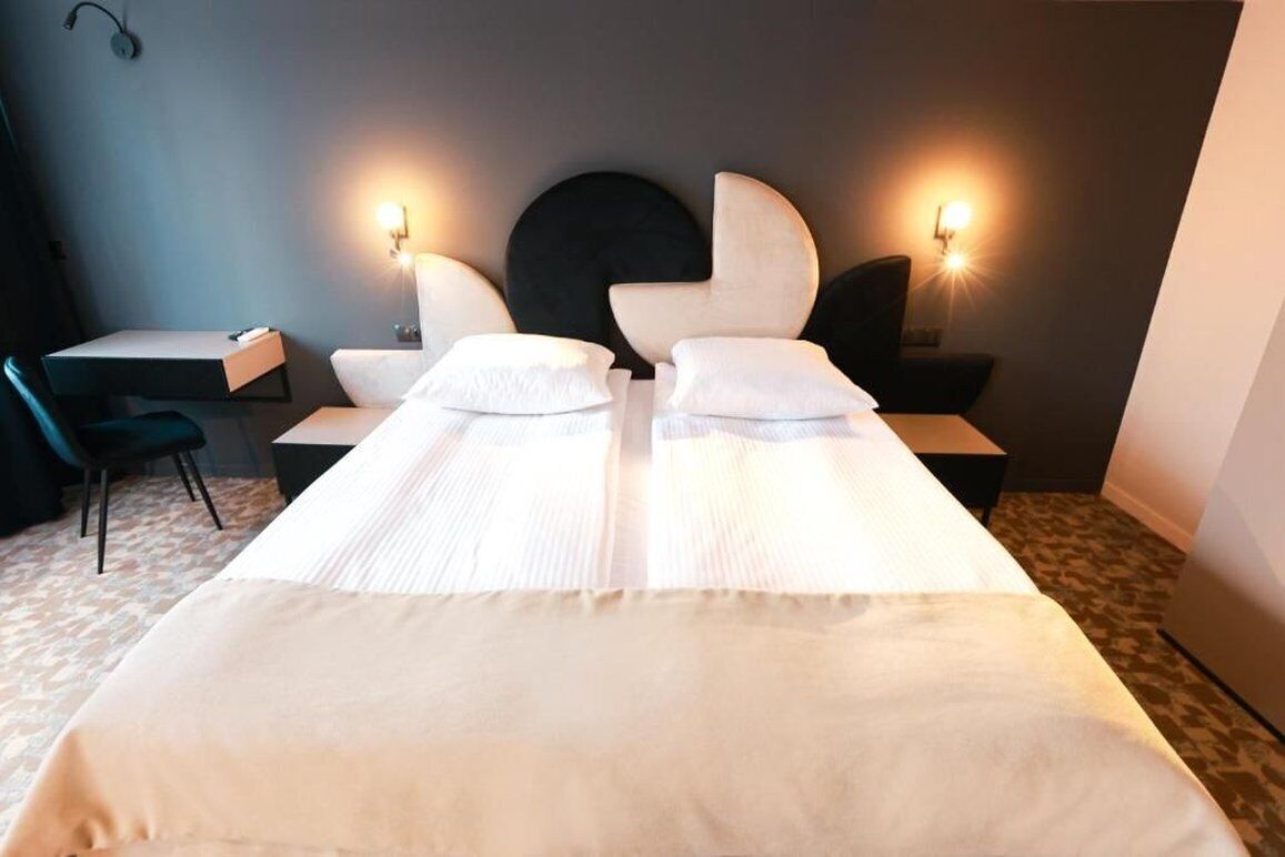 Hotelkamer met een groot bed, twee nachtkastjes, een bureau en twee wandlampen.