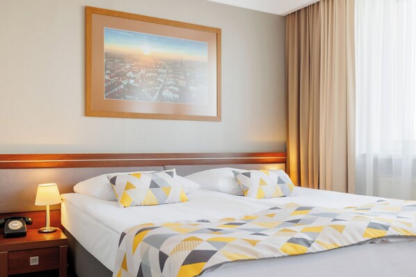 A hotel room with a bed, a nightstand with a lamp, and a framed picture on the wall. - Hotel Tarnovia (Tarnow)