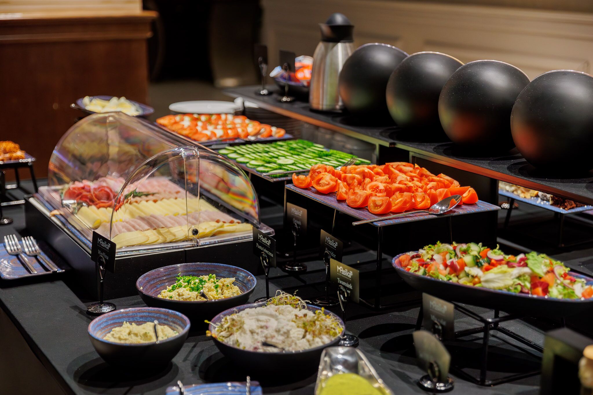 Ein Buffet mit verschiedenen Speisen, darunter Salate, Fleisch und Gemüse.