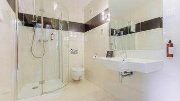 A modern bathroom with a glass-enclosed shower, a toilet, and a sink with a mirror above it.