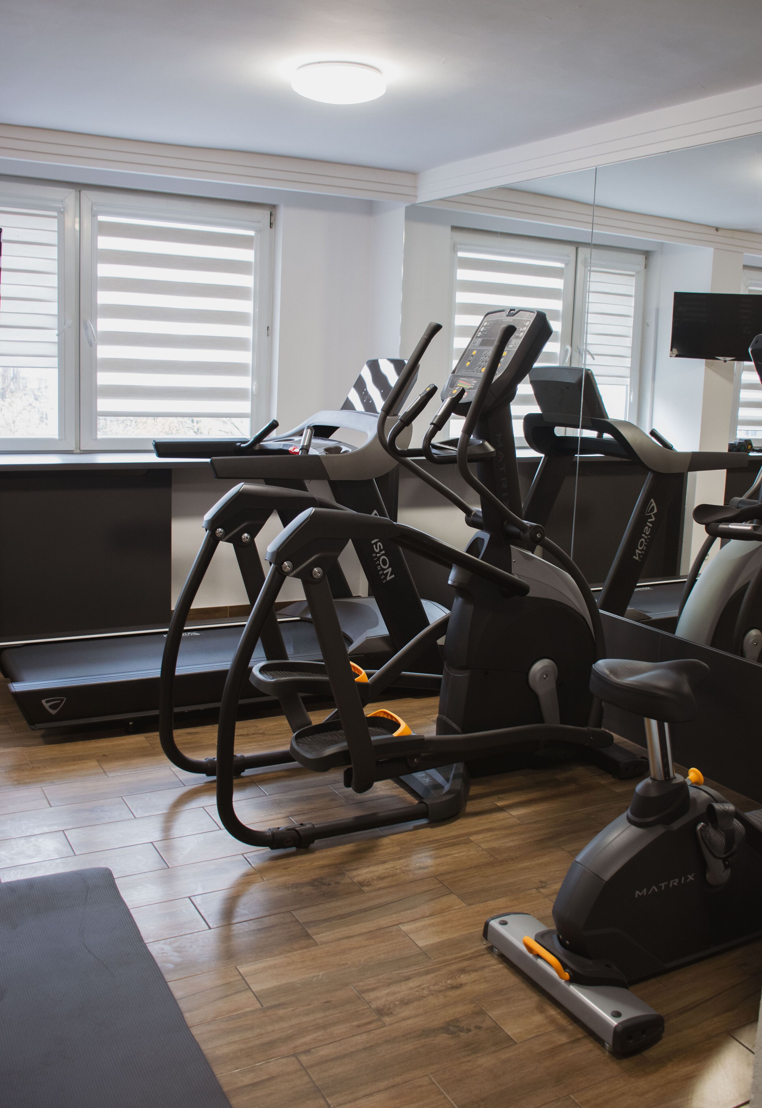Une salle de sport équipée de tapis de course, de vélos d’appartement et d’un appareil d’aviron.