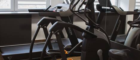 Une salle de sport équipée de tapis de course, de vélos d’appartement et d’un appareil d’aviron.