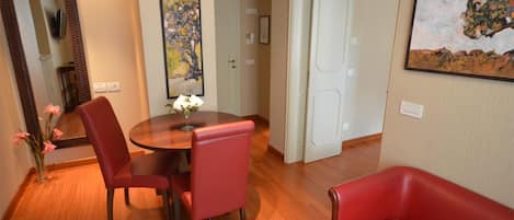 Un comedor con una mesa redonda, sillas rojas y un jarrón de flores.