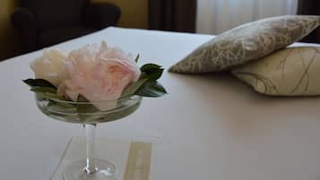 A bed with a white bedspread, a decorative glass bowl with flowers, and a pillow with a geometric pattern.