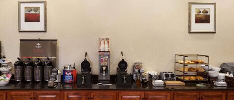 A breakfast bar with coffee makers, waffle makers, and a Quaker Oatmeal dispenser.