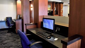Een hotel receptiebalie met een computer, twee stoelen en een grote spiegel.