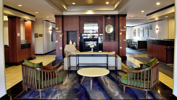 Een hotel lobby met een receptiebalie, een zithoek met een ronde tafel en een bar.