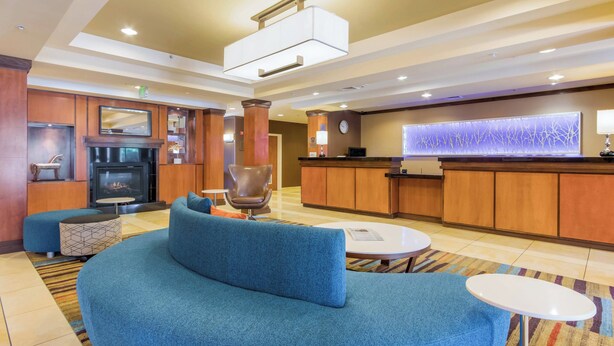 A lobby with a blue sofa, a fireplace, a reception desk, and a decorative wall. - Fairfield Inn & Suites by Marriott Columbia (Columbia)