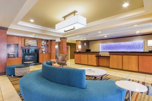 A lobby with a blue sofa, a fireplace, a reception desk, and a decorative wall. - Fairfield Inn & Suites by Marriott Columbia (Columbia)