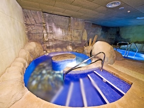 A hot tub with a stone wall backdrop, a wooden platform, and a metal ladder. - Senator Granada Hotel (Granada)