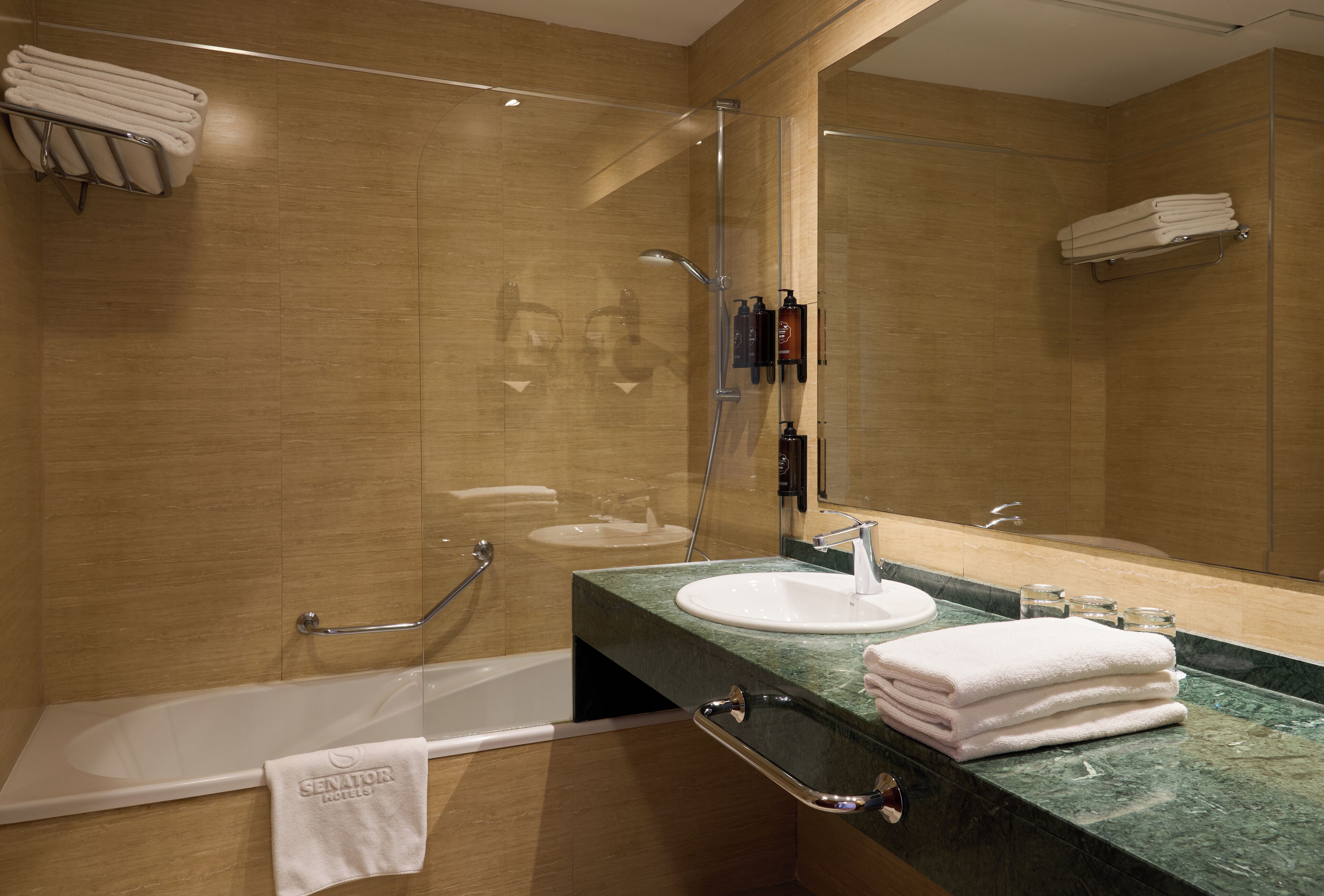 A modern bathroom with a bathtub, a sink, and a shower. There are towels stacked on a shelf and a glass shower enclosure.