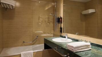 A modern bathroom with a bathtub, a sink, and a shower. There are towels stacked on a shelf and a glass shower enclosure.