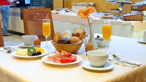 Un bufé de desayuno con diversos alimentos, como frutas, bollería y bebidas.